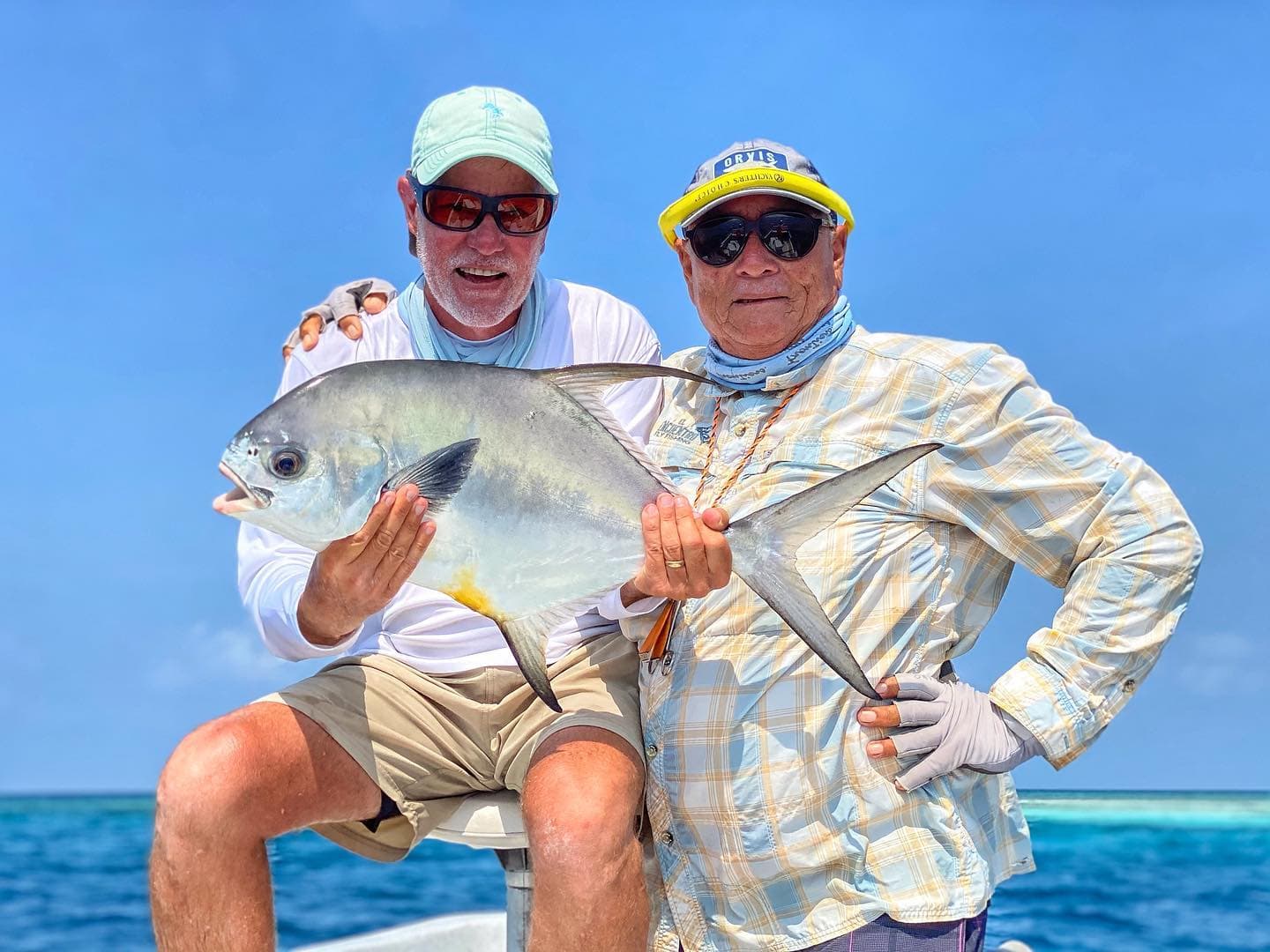 Charlie Leslie and an angler holding a permit aboard a boat